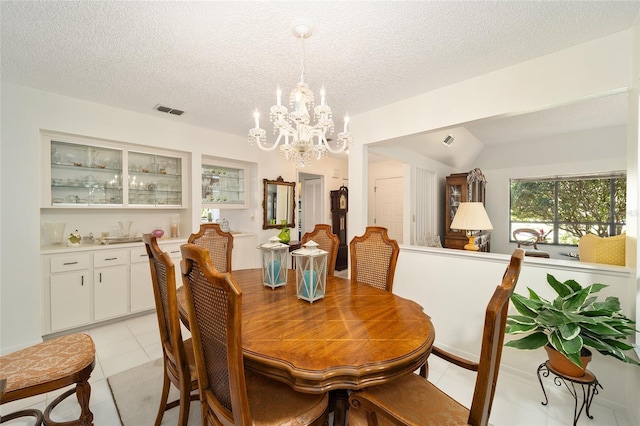 dining area featuring a chandelier, visible vents, a textured ceiling, and light tile patterned flooring