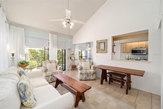 living area featuring light tile patterned floors, ceiling fan, high vaulted ceiling, and a textured ceiling