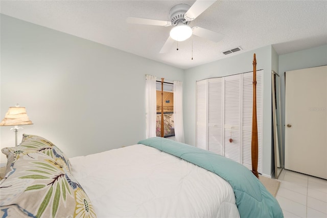 bedroom with visible vents, a ceiling fan, a textured ceiling, a closet, and light tile patterned flooring