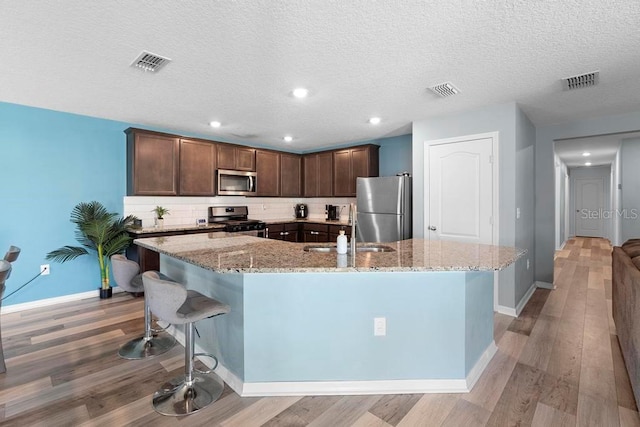 kitchen featuring light wood-style floors, visible vents, stainless steel appliances, and a sink