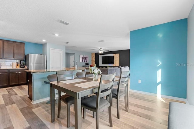 dining area with light wood-style floors, visible vents, ceiling fan, and baseboards