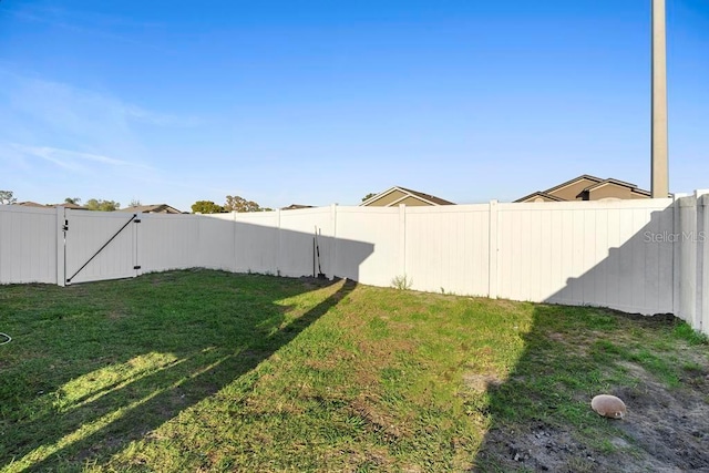 view of yard with a fenced backyard and a gate