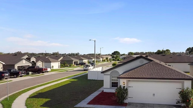 view of front of home with an attached garage, a residential view, concrete driveway, and stucco siding