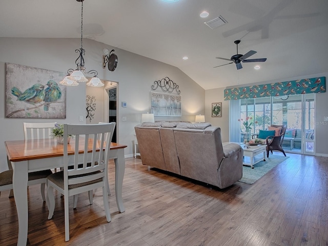 living room featuring lofted ceiling, light wood finished floors, visible vents, and a ceiling fan