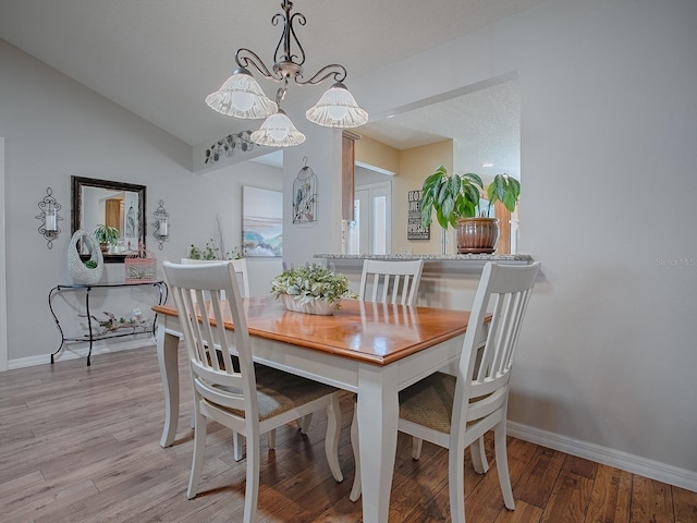 dining room with light wood-type flooring, lofted ceiling, and baseboards