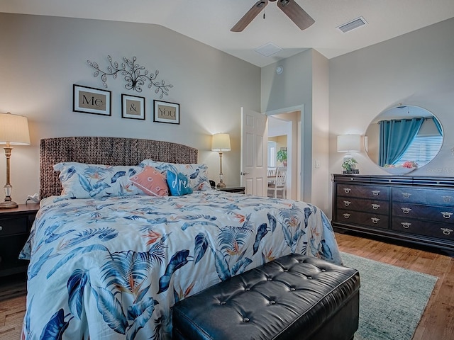 bedroom with vaulted ceiling, wood finished floors, visible vents, and a ceiling fan