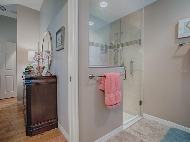 full bath featuring a shower stall, visible vents, baseboards, and wood finished floors