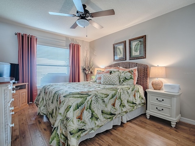 bedroom featuring hardwood / wood-style flooring, baseboards, a ceiling fan, and a textured ceiling