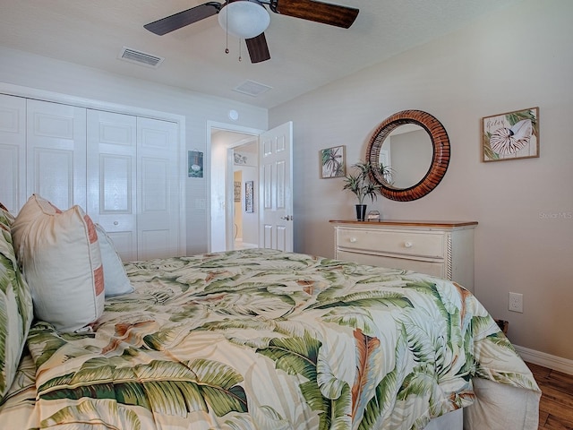 bedroom featuring wood finished floors, visible vents, baseboards, a ceiling fan, and a closet