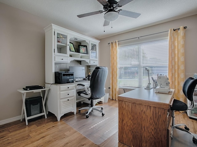 office with light wood finished floors, ceiling fan, baseboards, and a textured ceiling