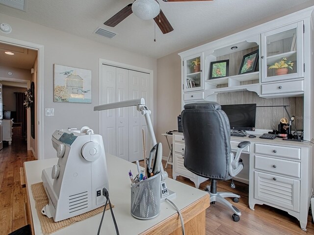 office area featuring light wood-style floors, visible vents, and a ceiling fan