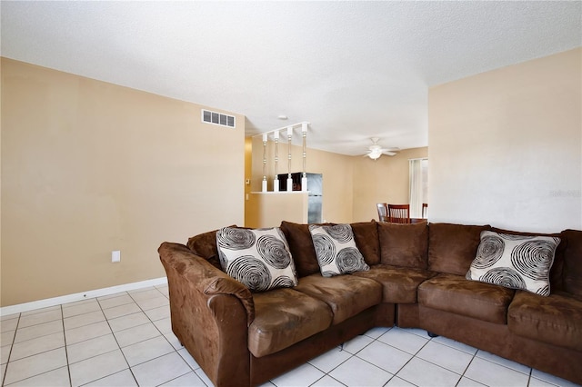 living area featuring light tile patterned floors, ceiling fan, a textured ceiling, visible vents, and baseboards