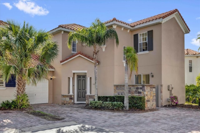 mediterranean / spanish-style home featuring decorative driveway, a tile roof, and stucco siding