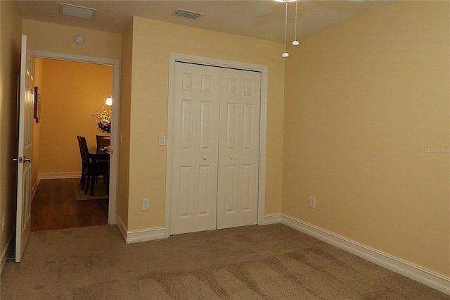 unfurnished bedroom featuring a closet, carpet, visible vents, and baseboards