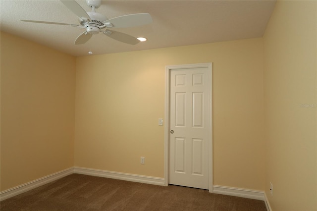 spare room with ceiling fan, dark carpet, and baseboards