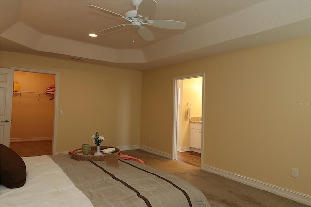 bedroom featuring baseboards, a raised ceiling, and light colored carpet