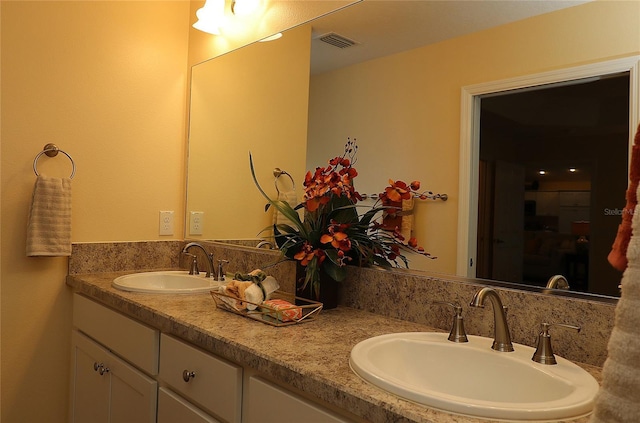 bathroom with double vanity, a shower, a sink, and visible vents