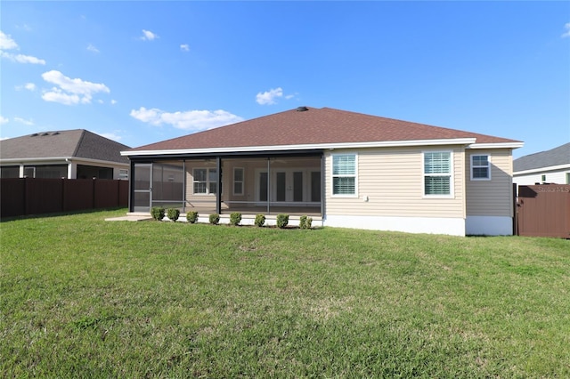 back of property featuring a lawn, fence, and a sunroom