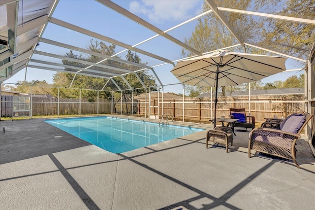 view of pool with glass enclosure, a patio area, a fenced backyard, and a fenced in pool