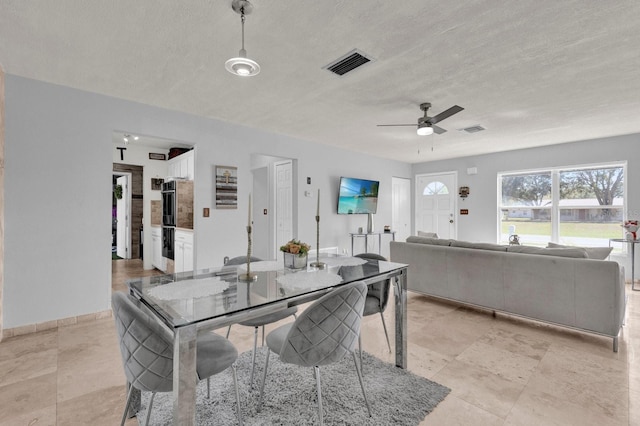 dining space with baseboards, visible vents, a textured ceiling, and ceiling fan