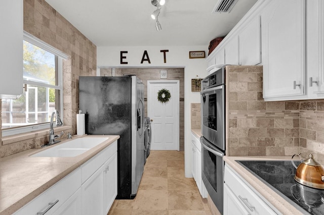 kitchen featuring visible vents, backsplash, stainless steel fridge with ice dispenser, black electric cooktop, and a sink