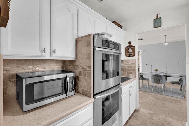 kitchen featuring decorative backsplash, white cabinetry, and stainless steel appliances