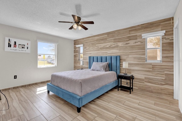 bedroom featuring multiple windows, a ceiling fan, baseboards, and a textured ceiling