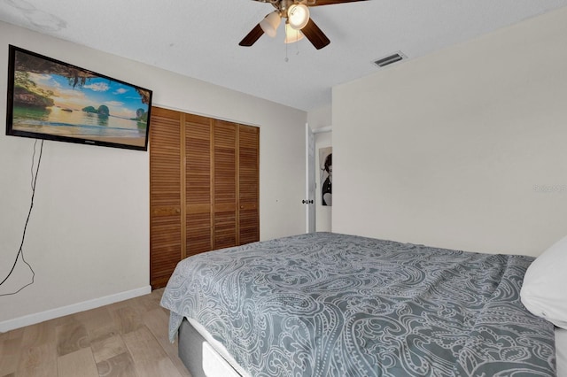 bedroom featuring visible vents, baseboards, light wood-style flooring, ceiling fan, and a closet