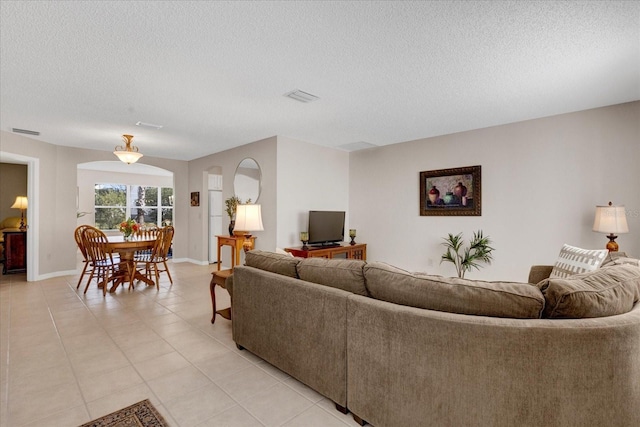 living room featuring baseboards, visible vents, a textured ceiling, and light tile patterned flooring