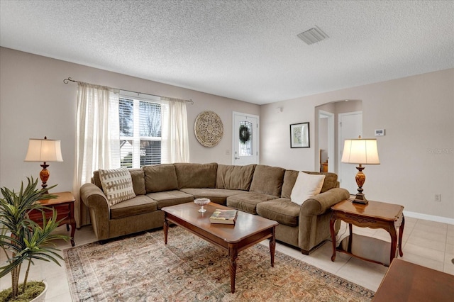 living area with visible vents, a textured ceiling, baseboards, and light tile patterned floors