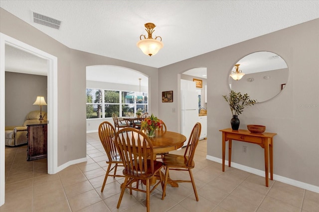 dining space featuring light tile patterned floors, baseboards, visible vents, and a textured ceiling