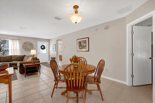 dining space with light tile patterned floors, baseboards, visible vents, and a textured ceiling