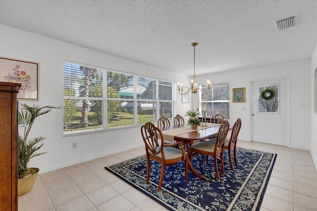 dining room featuring light tile patterned floors, a textured ceiling, visible vents, and an inviting chandelier