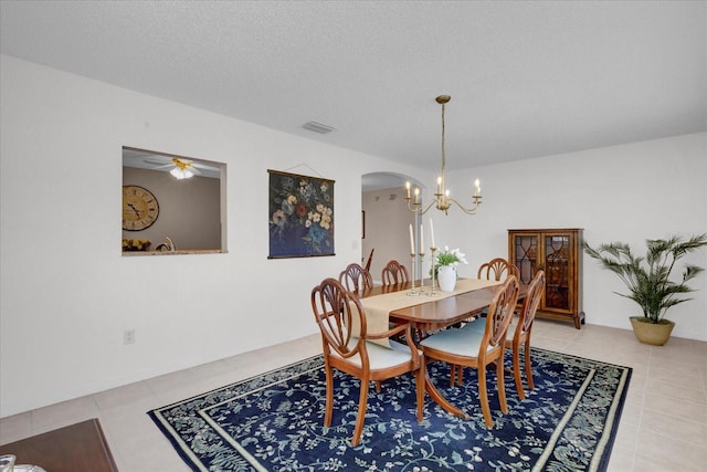 dining area featuring visible vents, arched walkways, a textured ceiling, a chandelier, and light tile patterned flooring