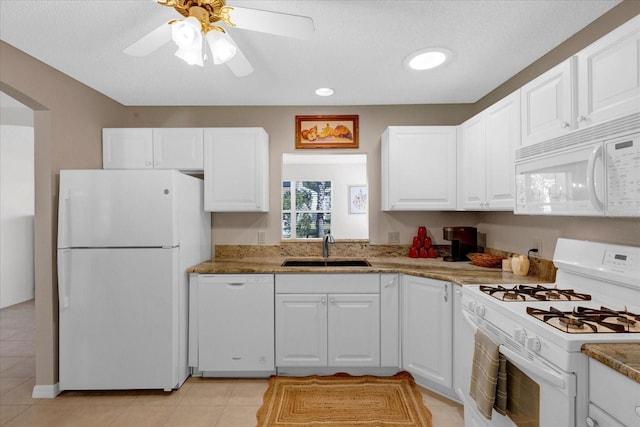 kitchen with white appliances, arched walkways, white cabinets, and a sink