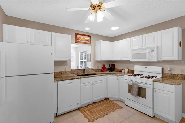 kitchen featuring light tile patterned floors, white cabinets, a sink, ceiling fan, and white appliances