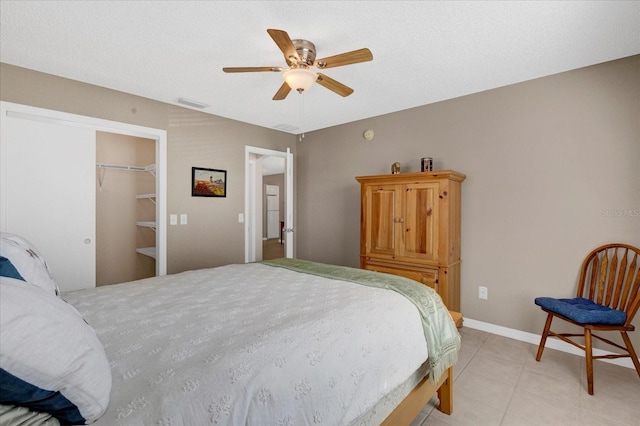 bedroom with light tile patterned floors, baseboards, visible vents, a ceiling fan, and a spacious closet