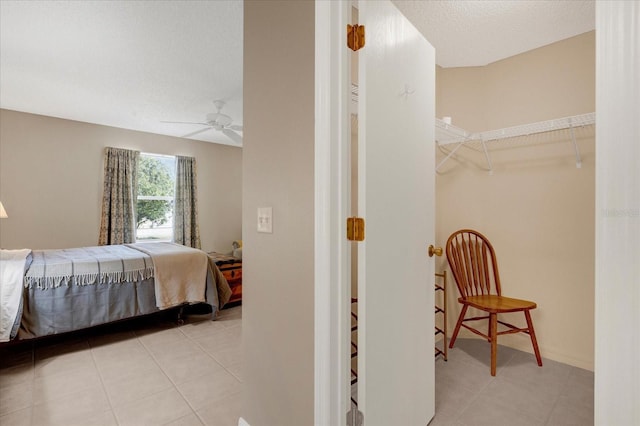 tiled bedroom with a textured ceiling, a ceiling fan, and baseboards