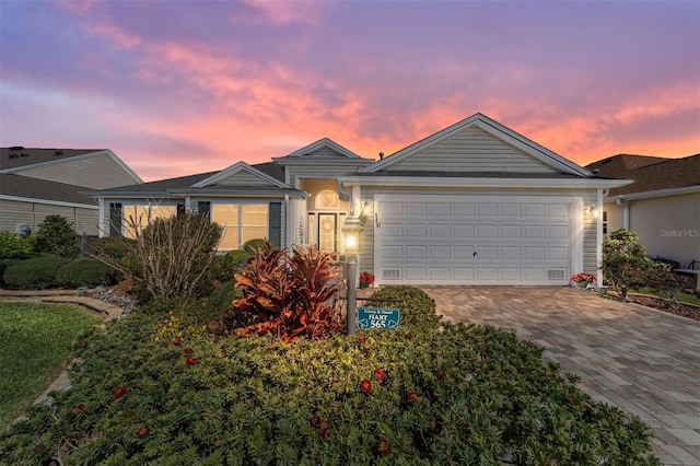 ranch-style home with a garage and decorative driveway