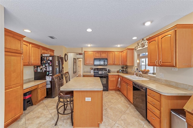 kitchen with a kitchen island, a kitchen breakfast bar, light countertops, black appliances, and a sink