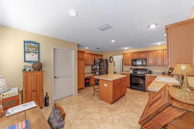 kitchen featuring a breakfast bar, visible vents, light countertops, a center island, and black appliances