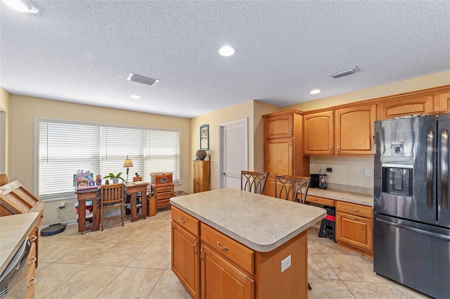 kitchen with light tile patterned floors, visible vents, a center island, fridge with ice dispenser, and light countertops