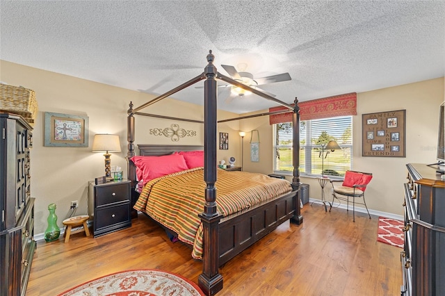 bedroom featuring a ceiling fan, a textured ceiling, baseboards, and wood finished floors