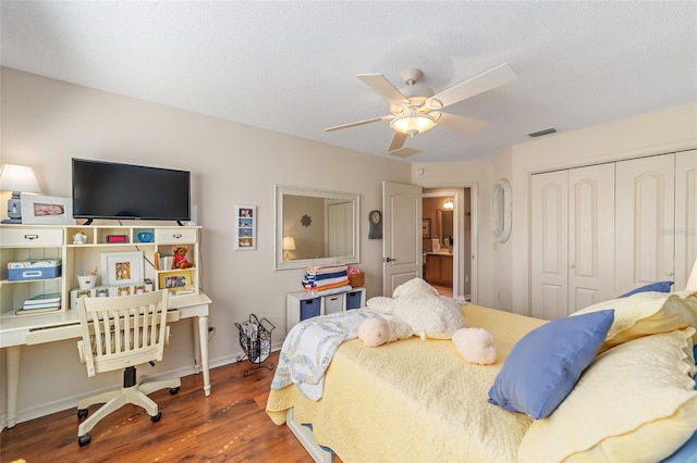 bedroom with a closet, visible vents, ceiling fan, a textured ceiling, and wood finished floors