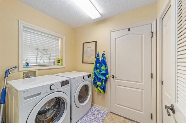 laundry area with laundry area, light tile patterned floors, baseboards, a textured ceiling, and separate washer and dryer