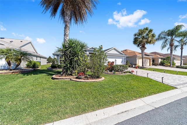 view of front facade with a garage, a residential view, decorative driveway, and a front yard