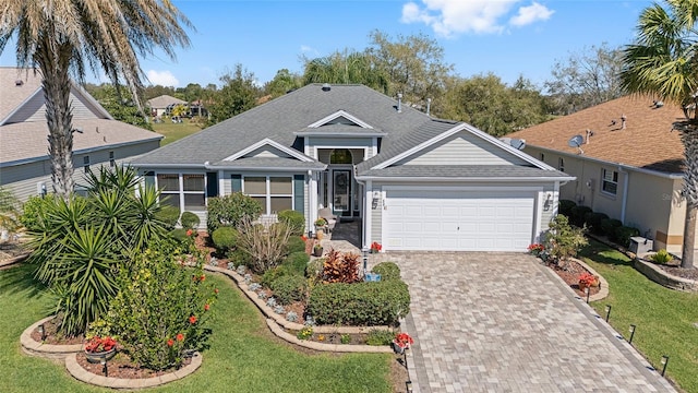 ranch-style home with roof with shingles, decorative driveway, an attached garage, and a front yard