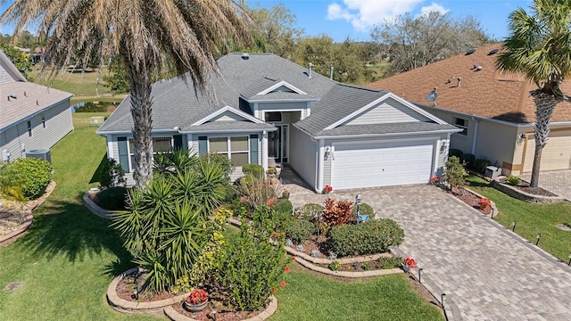 view of front of property featuring a front lawn, decorative driveway, an attached garage, and a shingled roof