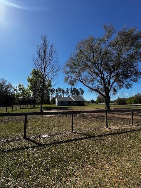 view of yard with fence and a rural view