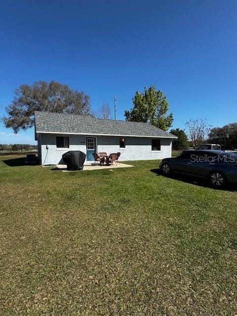 rear view of house featuring a yard and a patio